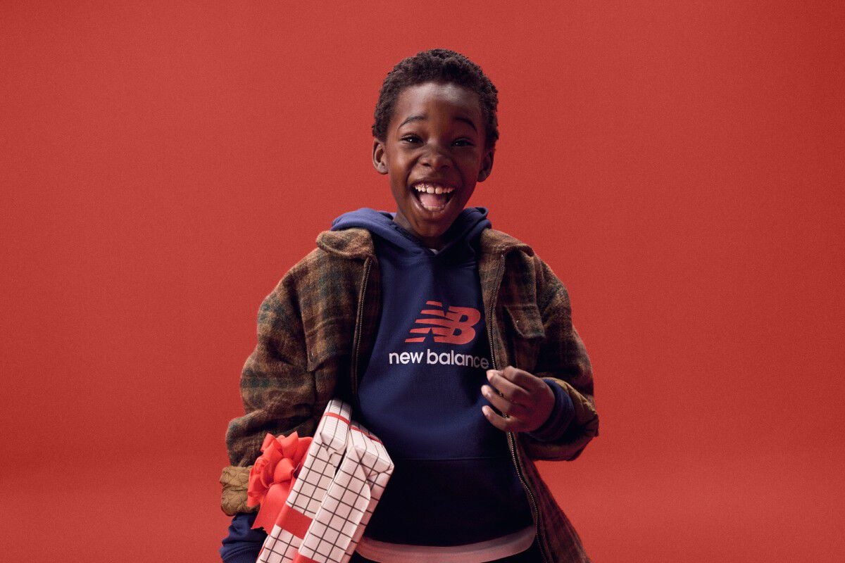 Kid laughing while holding gifts on a red background.