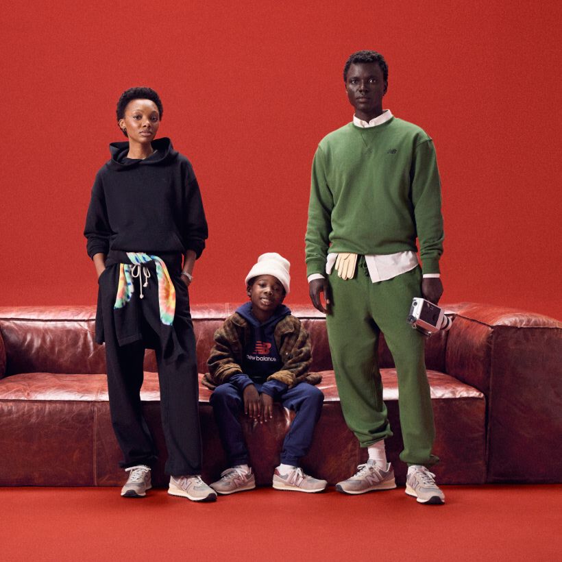 Family sitting around a red couch on a red backgroud.