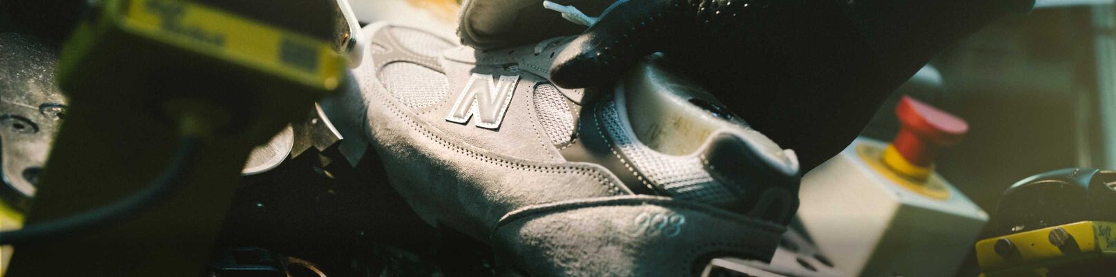 A hand putting a shoe in a device in a factory environment.
