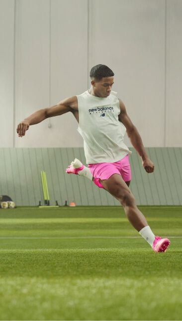 A soccer player with pink shorts in the motion of kicking a ball
